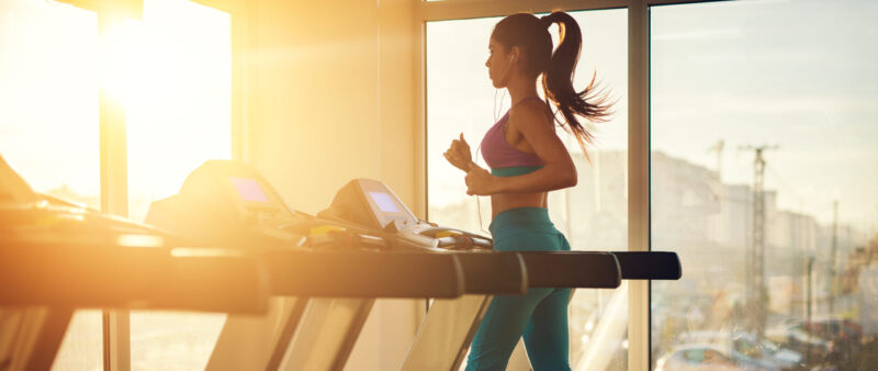 A person running on a treadmill in a health club in the morning sunshine - a symbol of energy and motivation for training.