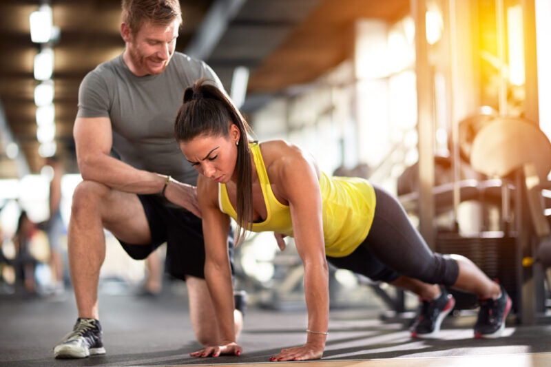 A personal trainer supports a woman during weight training at the Just GYM fitness club.