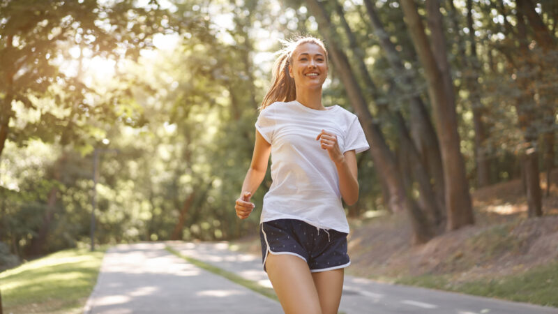 A person running down a forest alley on a sunny day - a symbol of motivation and working on form before summer.