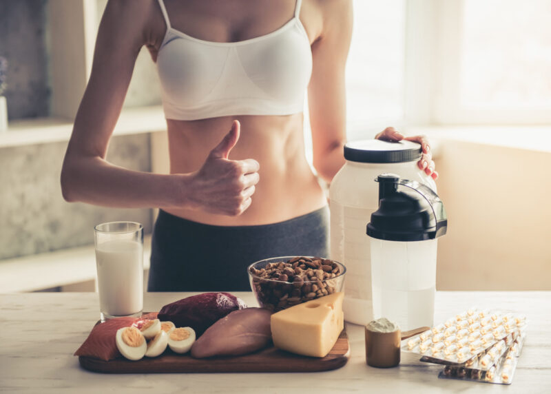 Trainer showing thumb up next to protein-rich products and protein supplement