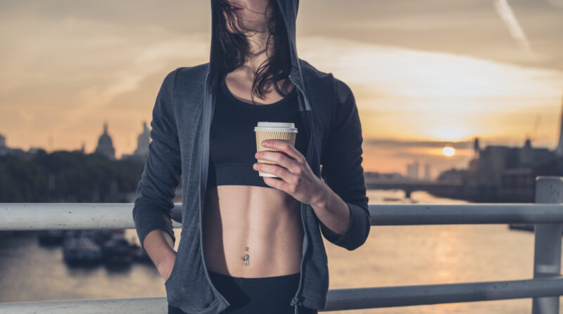 A person in sportswear holding a cup of coffee after a workout - a natural source of energy for the active.
