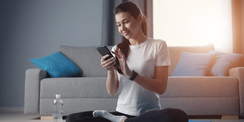 Woman checking workout progress on fitness app after exercising at home