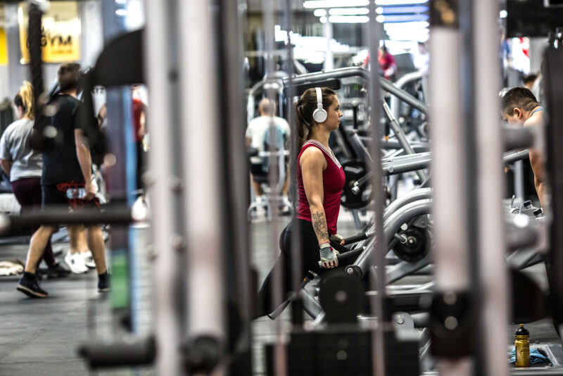 Strength training at Just Gym Lublin - a woman performing exercises with dumbbells among the weight training equipment.