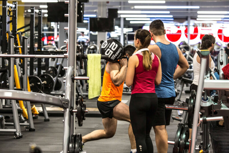 A group of people training in the free weights area of Just Gym Lublin - modern fitness equipment and professional training conditions.