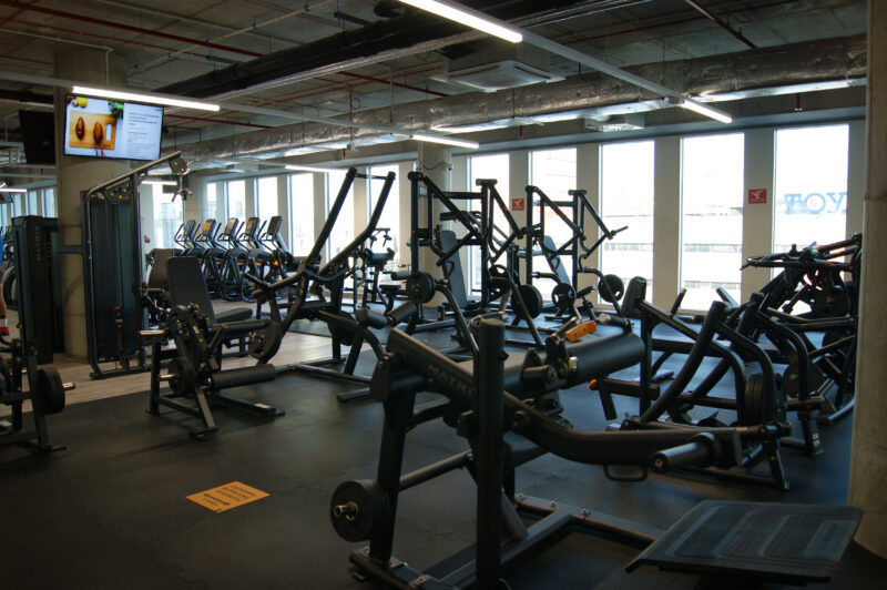 A modern workout space at the Just Gym Łódź Piotrkowska with weight training machines and a cardio zone.