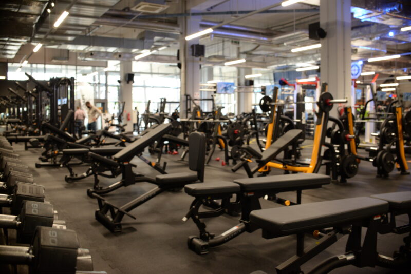 The gym area at Just Gym Poznań Bulgarska - benches, dumbbells and exercise machines in a modern club interior.