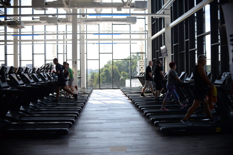 Rzędy bieżni w siłowni Just Gym Jastrzębie-Zdrój, z ćwiczącymi osobami i dużymi oknami wpuszczającymi naturalne światło.