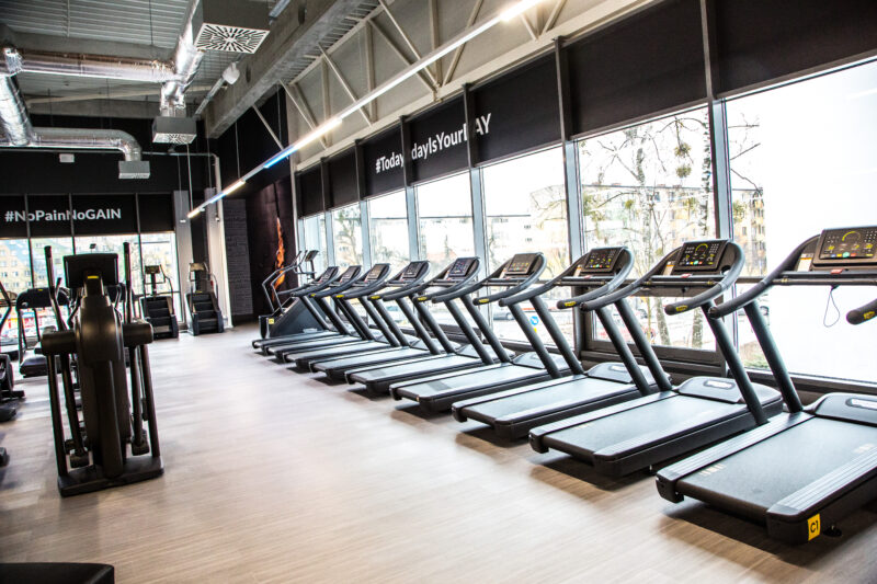 Strefa cardio Just Gym Radom – rząd bieżni Technogym przy przeszklonej ścianie z widokiem na miasto.