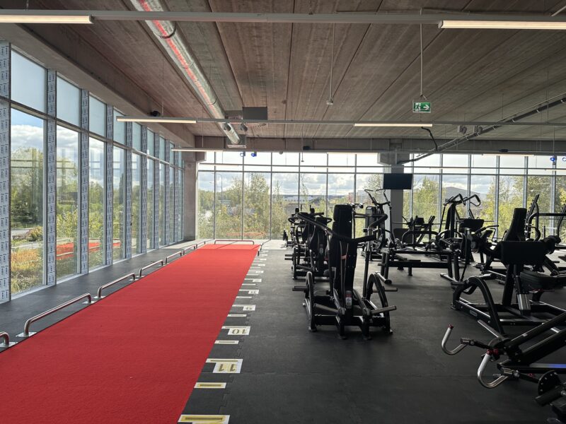 Strefa funkcjonalna Just Gym Ruda Śląska – czerwony tor treningowy i sprzęt do ćwiczeń siłowych przy przeszklonej ścianie.