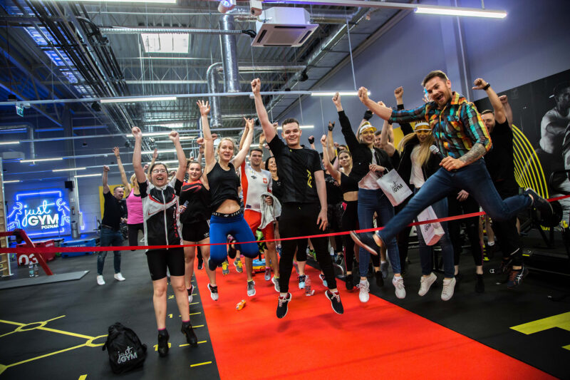 Just Gym Poznań Swiss Gym opening - a group of people celebrating the club's inauguration on the red training track.