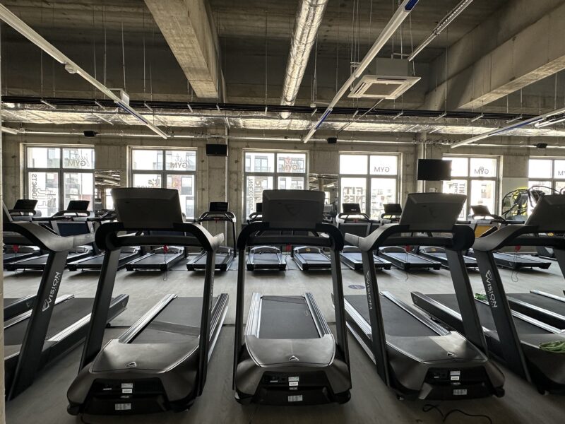 Just Gym Szczecin cardio zone - a row of Vision treadmills in a spacious, industrial hall with large windows.