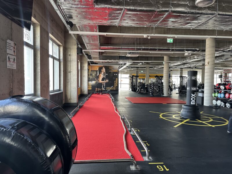 Red training track in the Just Gym Szczecin functional area - boxing bags and fitness equipment.
