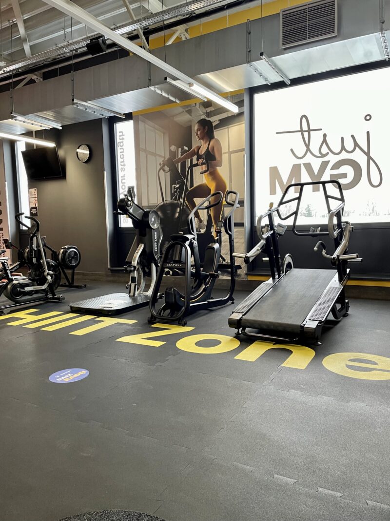 HIIT zone at Just Gym Gniezno with treadmills and cardio machines, in a modern interior with motivating graphics.