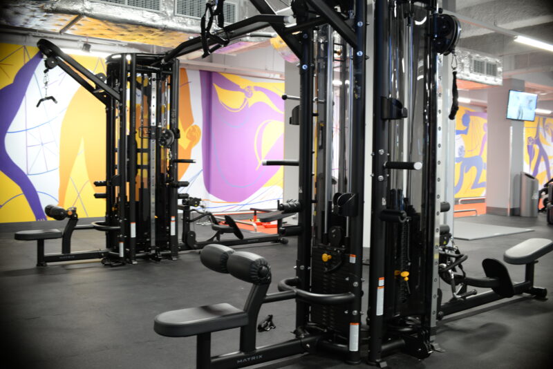 Maszyny treningowe w strefie siłowej Just Gym Łódź Rewolucji – nowoczesne urządzenia Matrix na tle kolorowej ściany.