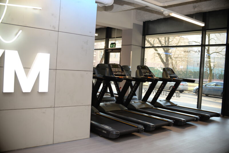 Nowoczesna strefa cardio w Just Gym Łódź Rewolucji – bieżnie Matrix ustawione przy dużych oknach z widokiem na miasto.