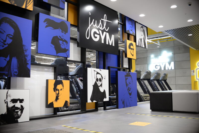 The entrance area of Just Gym Pabianice with the club's logo and modern decor in a yellow and black colour scheme.