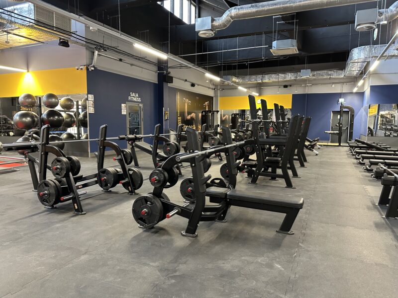 The free weights area at the Just Gym Częstochowa gym with a number of training benches and weight training machines.