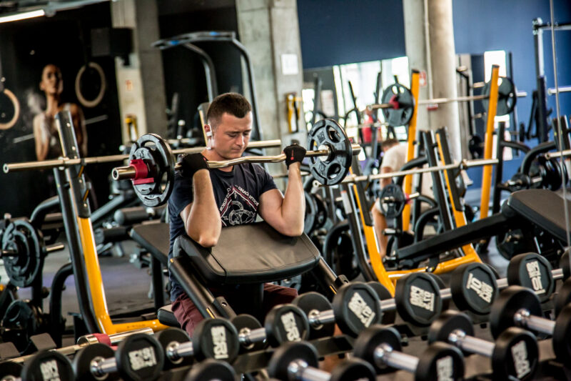 Just Gym Opole free weights zone - a person exercising with dumbbells and Matrix strength training machines.
