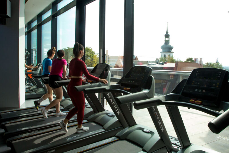 Treadmills at Just Gym Opole with a panoramic view of the city and the historic church tower.