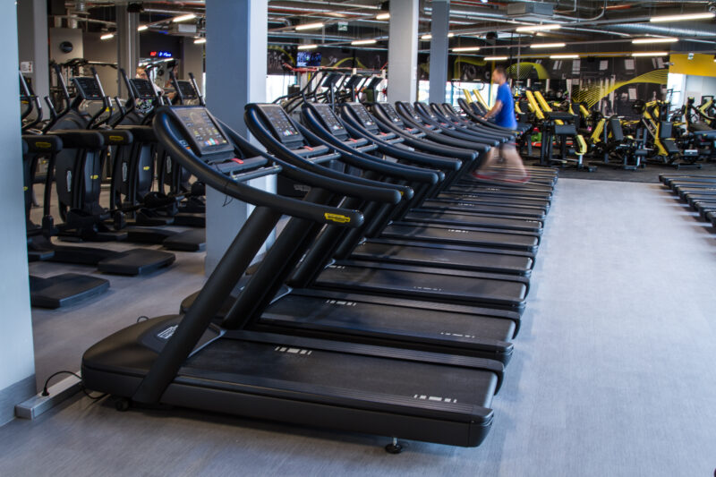 Just Gym Plock cardio zone - a row of modern Technogym treadmills in a spacious and bright room.