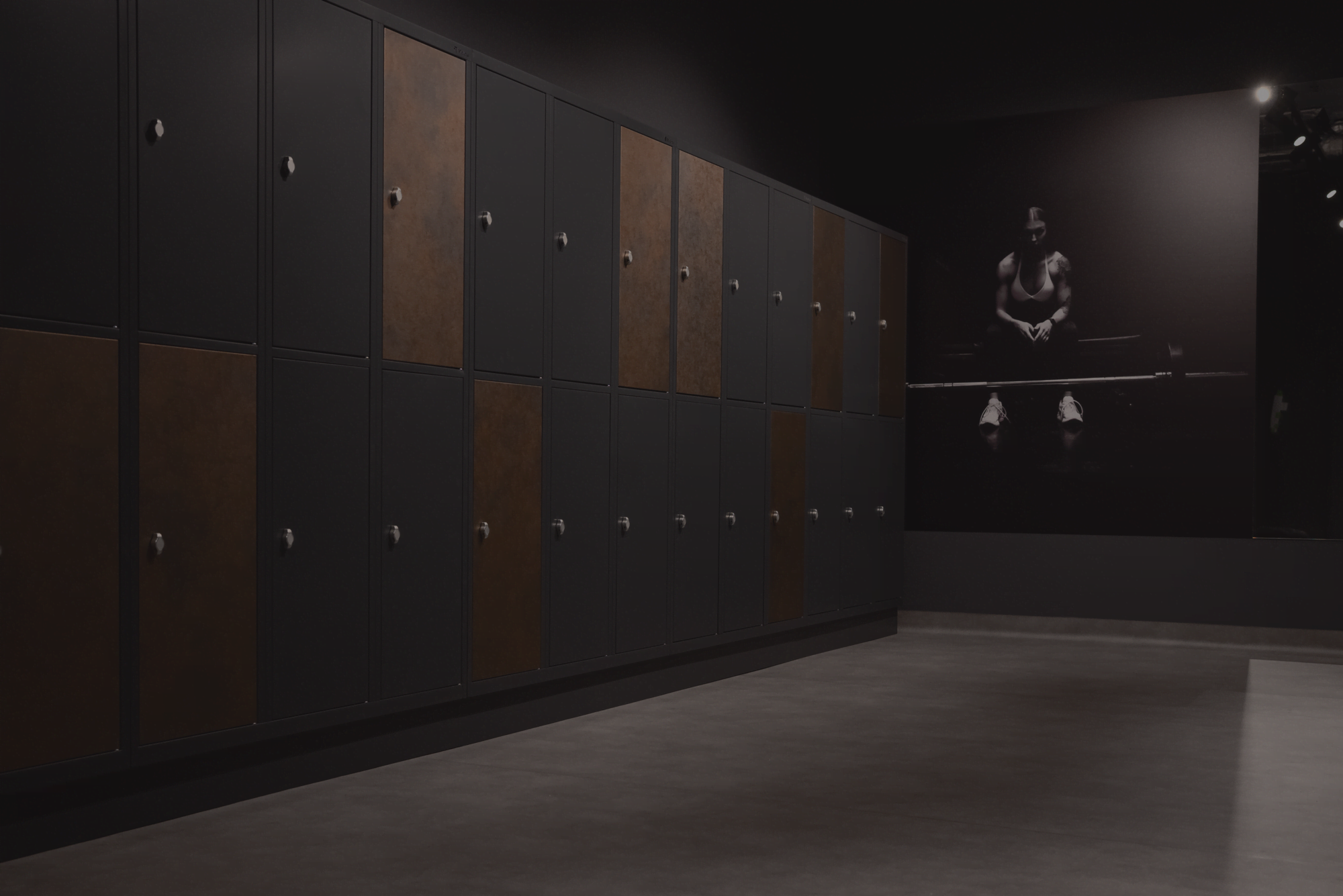The changing room at Just Gym Box Warsaw - a row of black and copper lockers and sports graphics on the wall.
