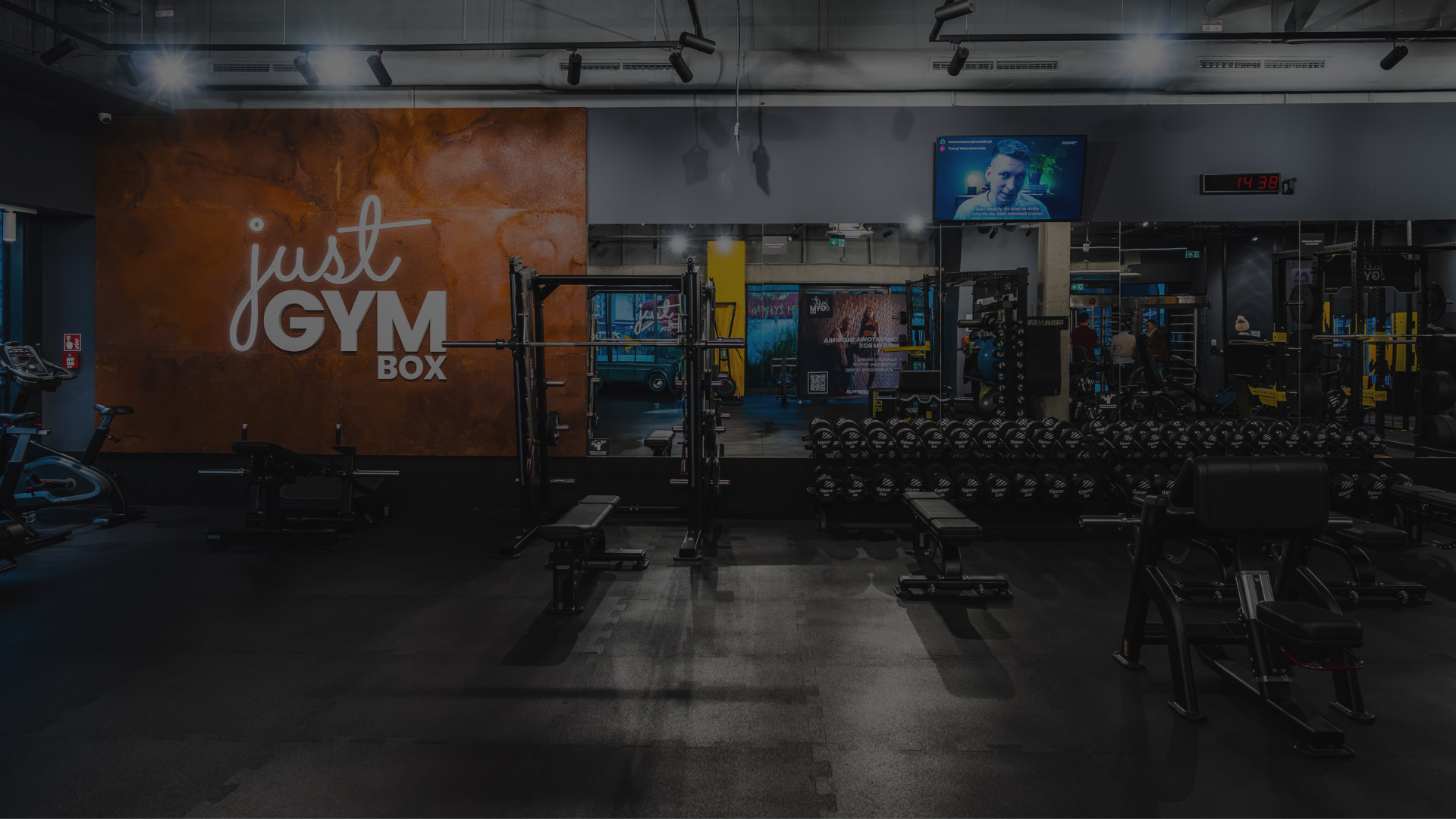 Wnętrze strefy cardio w klubie Just GYM BOX, wyposażone w bieżnie, trenażery eliptyczne i rowery stacjonarne. Pomieszczenie jest przestronne, z dużymi oknami i motywującymi napisami na ścianach.