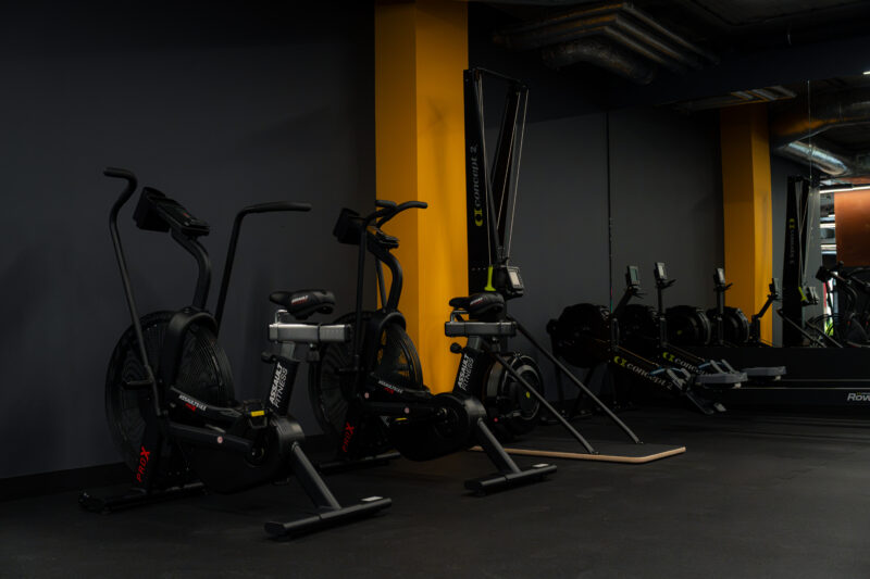 Strefa cardio na siłowni wyposażona w rowery powietrzne AssaultBike oraz ergometry wioślarskie.